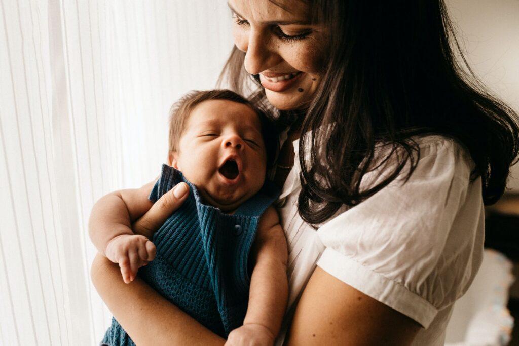A mother holds her yawning baby close.